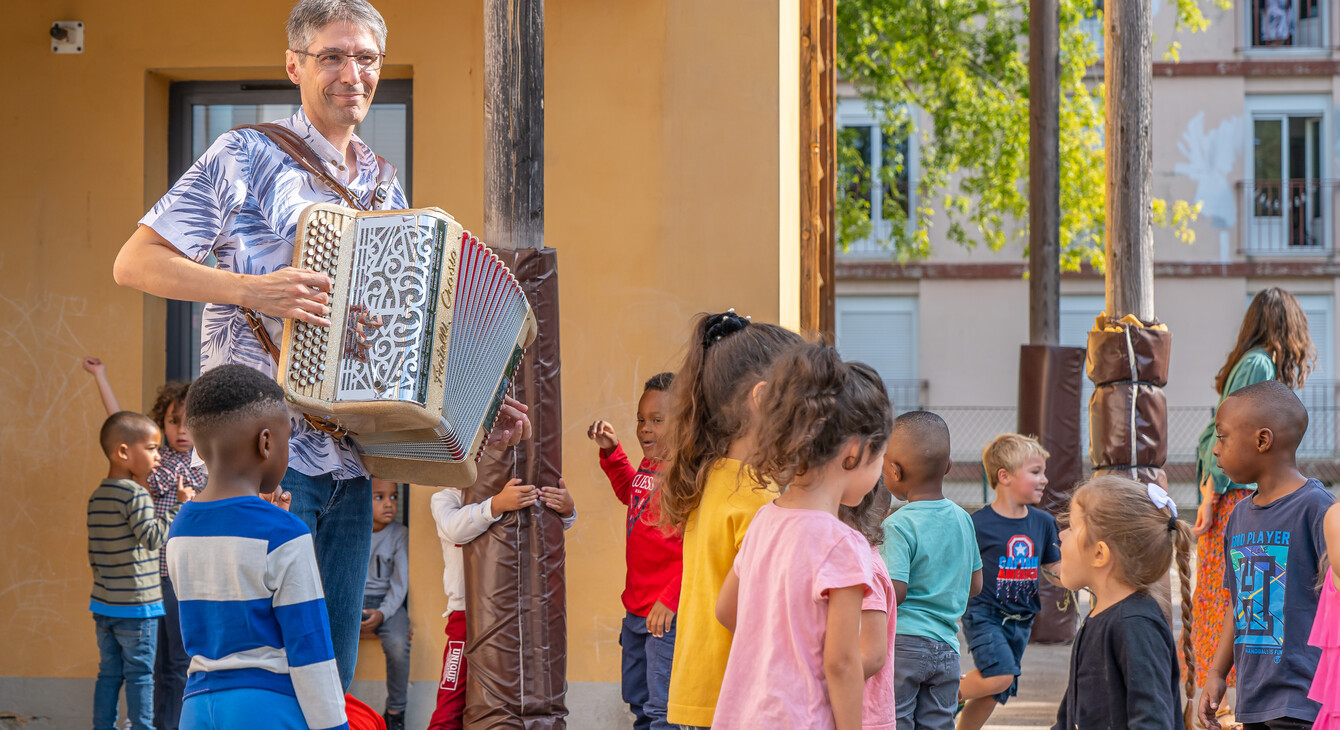 Un accordéoniste joue devant les élèves dans la cour de récréation pour la rentrée en musique